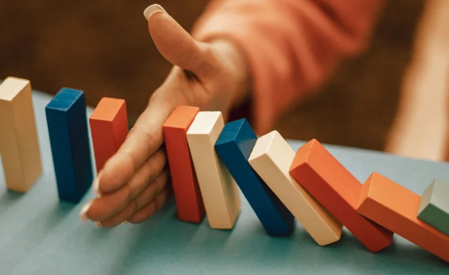 Hand stopping wooden blocks from continuing to tip over